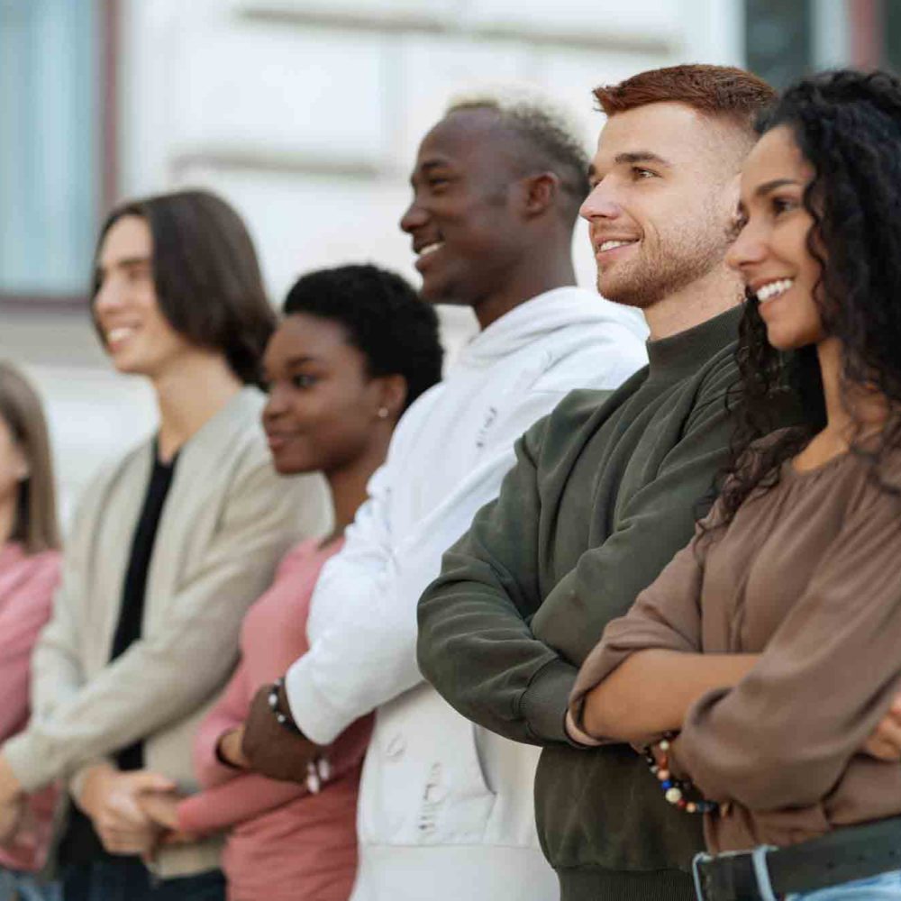 International group of cheerful students holding hands and chanting slogans while walking by street towards government building, multiracial activists having strike, feeling excited and invincible